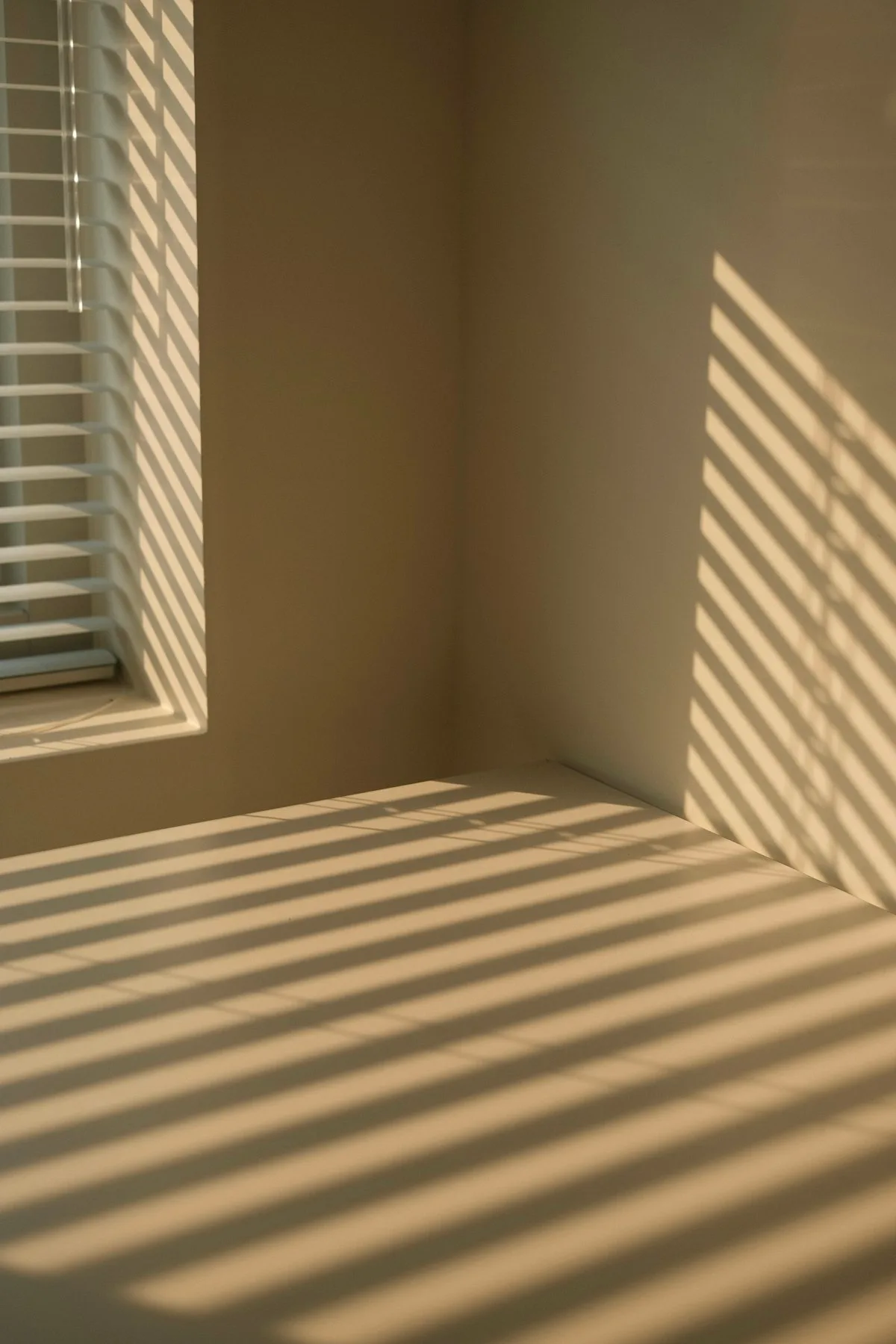 Luce di mattino che attraversa le veneziane — un respiro tra le tensioni