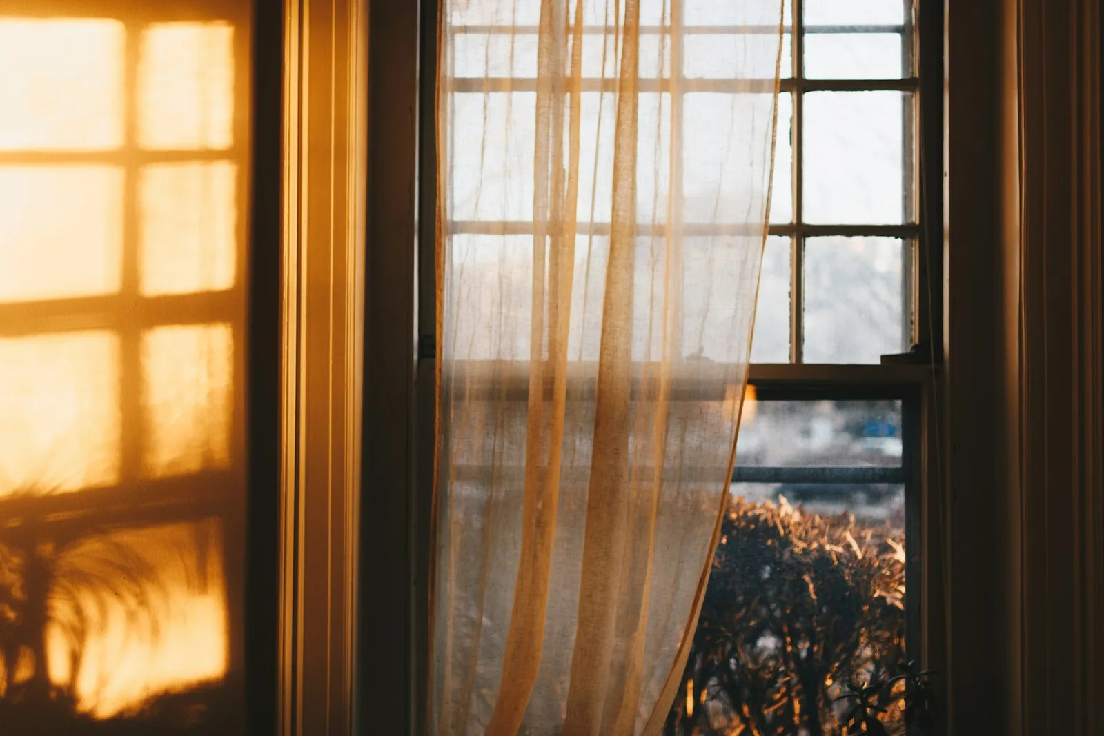 Tende beige attraversate da una luce calda di mattino — atmosfera dello studio di psicoterapia